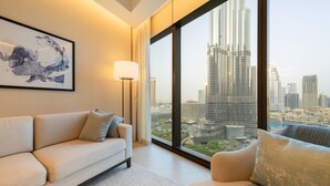 A modern living room with a sofa and armchairs, a floor lamp, and a large window offering a city view. - EDEN'S Homes & Villas - Address Opera District Residences (Dubai)