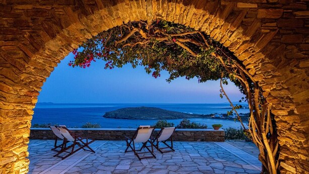 Un área de estar al aire libre con suelo de piedra y vistas al mar.