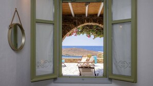 Habitación con vista al mar a través de una ventana abierta con contraventanas verdes.