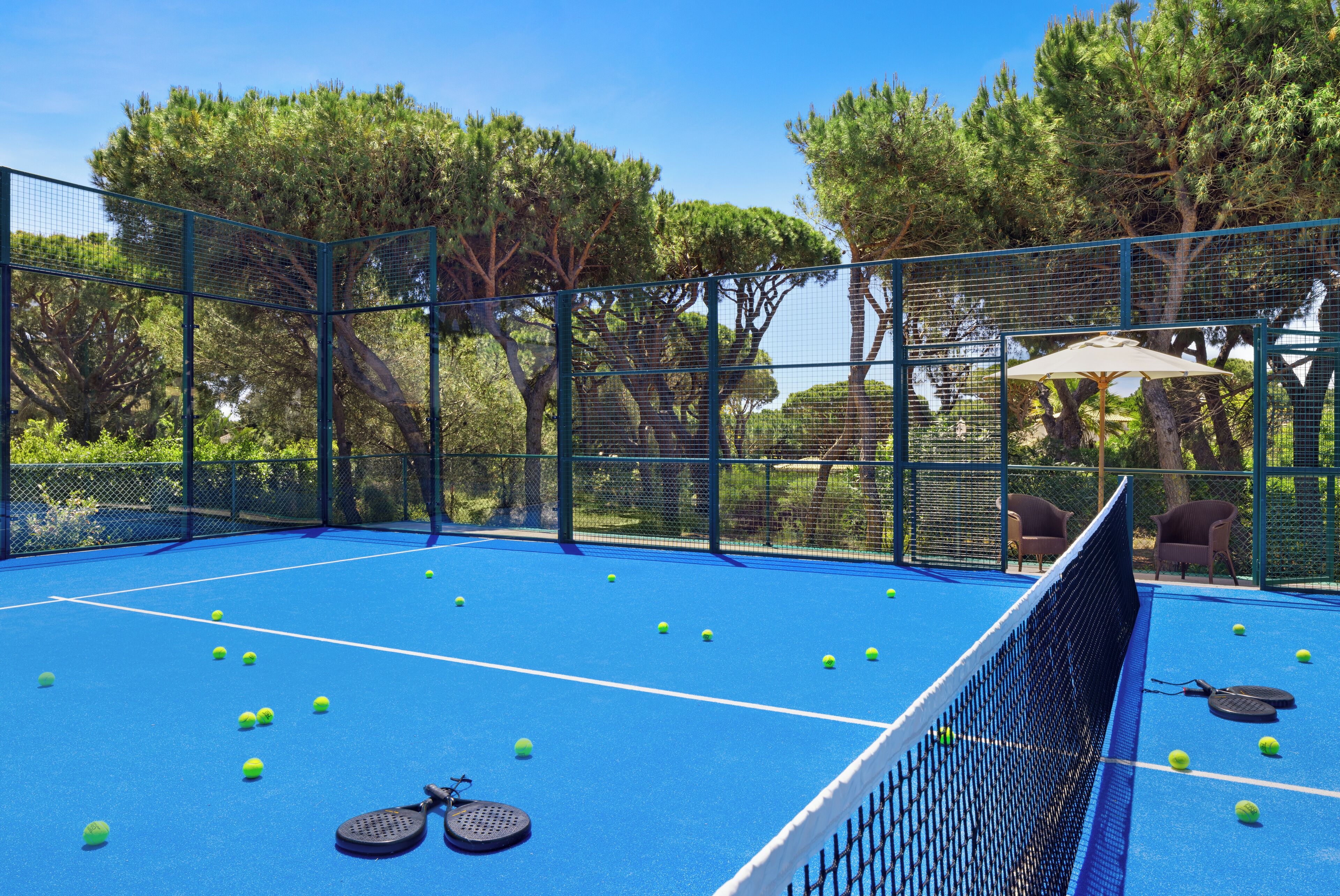 An outdoor tennis court with a net, tennis balls, and rackets.