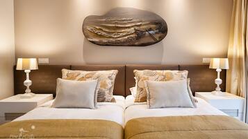 Cama de casal com duas mesas de cabeceira, cada uma com uma luminária, e um objeto decorativo na parede acima da cama.