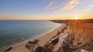 Paisatge costaner amb una platja, penya-segades i un capvespre.