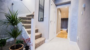 Eine Treppe mit beigefarbenem Teppich, einem Glasgeländer und einem Blumentopf links.