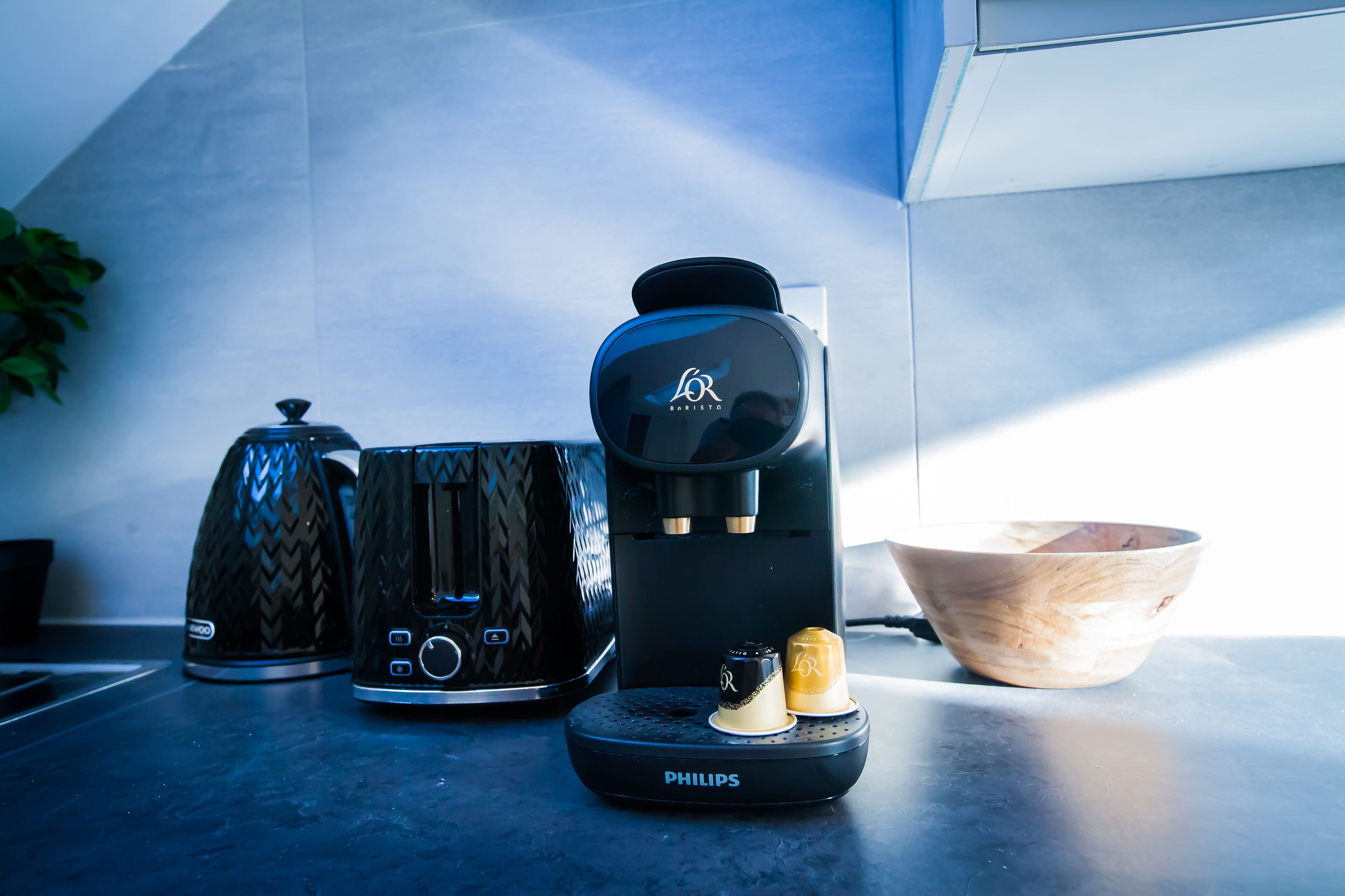 A coffee maker, a kettle, and a bowl on a kitchen counter.