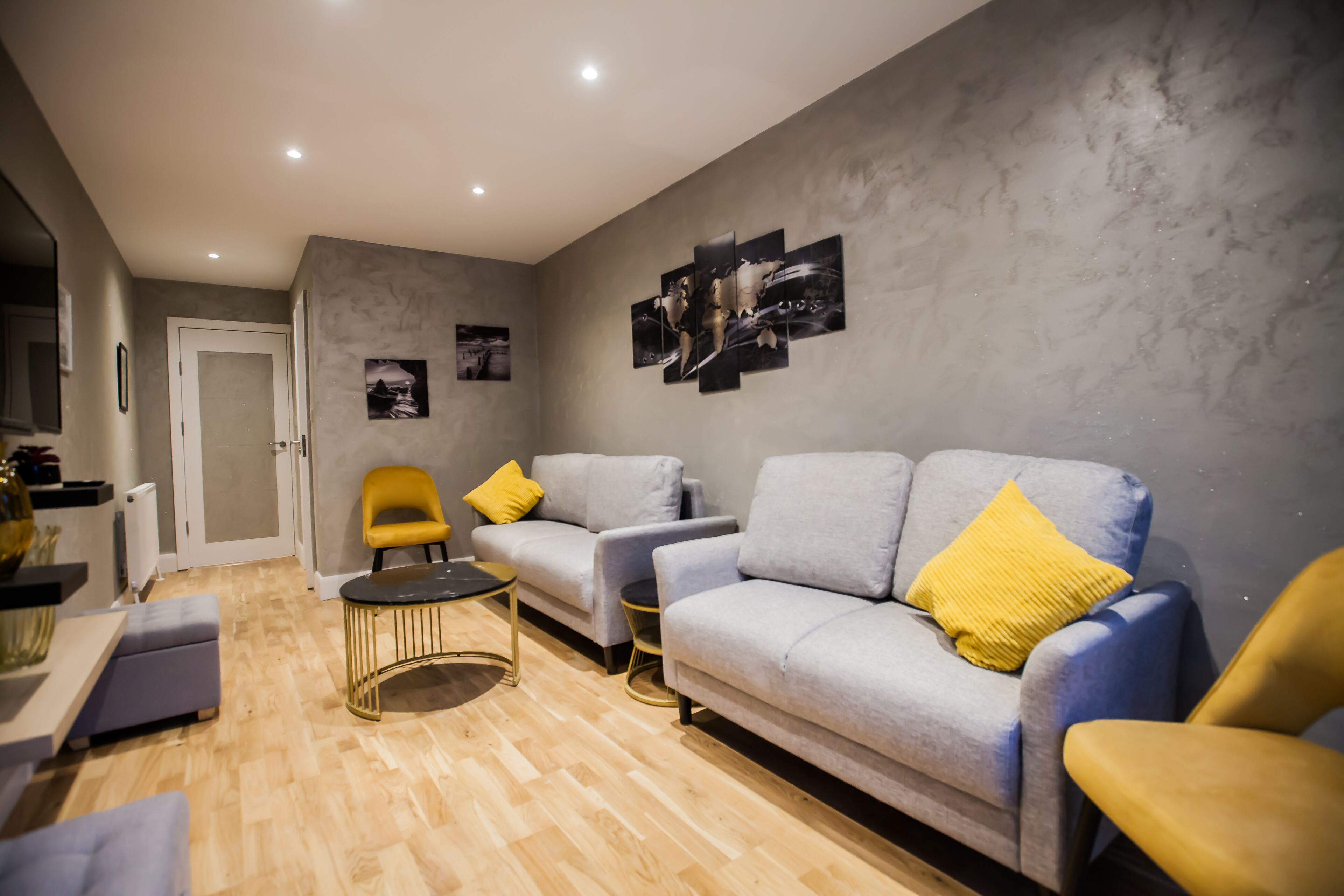 A modern living room with a grey sofa, a yellow armchair, and a round coffee table.