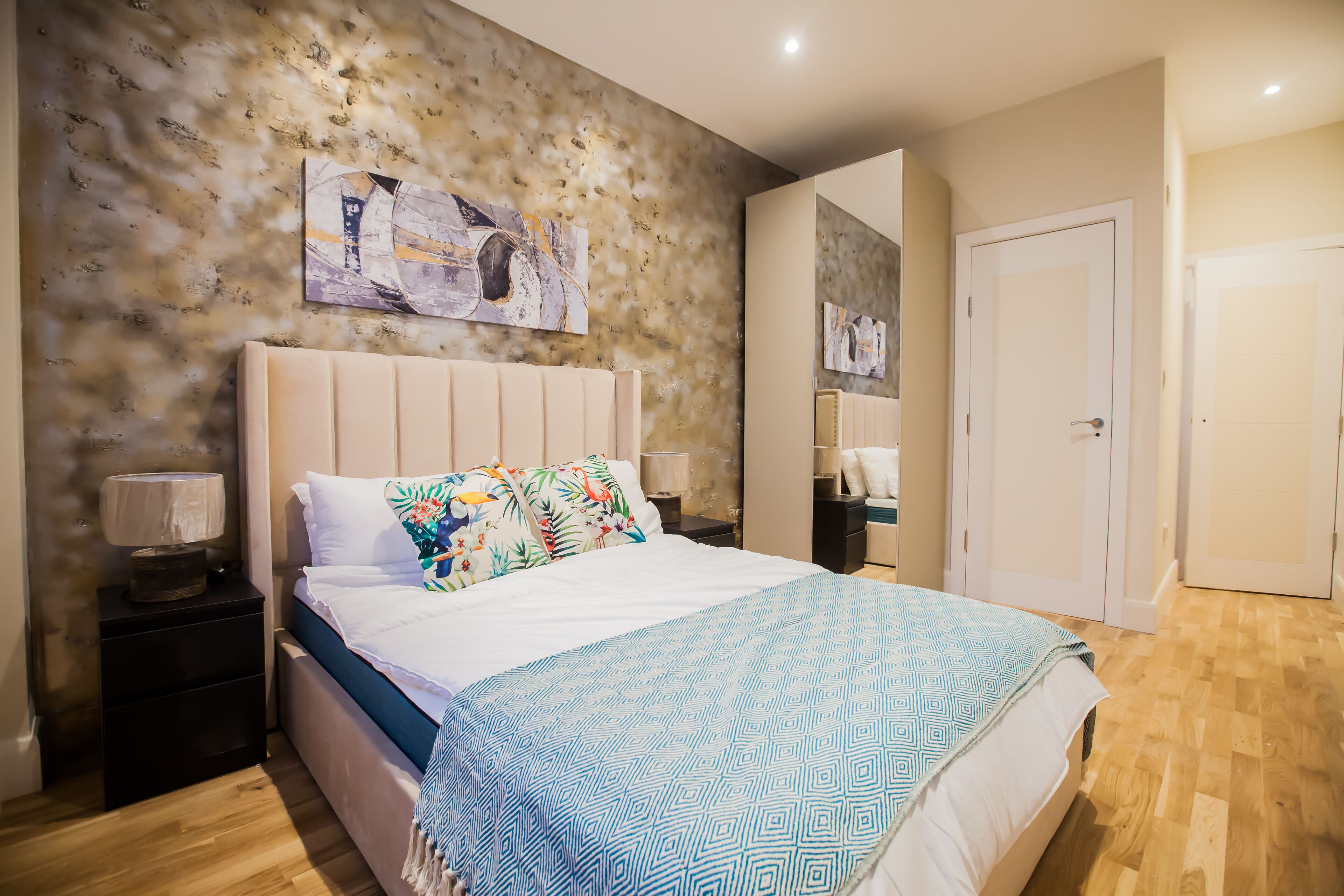 A bedroom with a bed, nightstands, and a wall-mounted artwork.