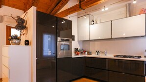 Een moderne keuken met zwarte apparaten, witte kasten en houten vloeren.