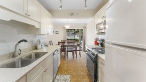 A modern kitchen with white cabinetry, a double sink, a stove, and a refrigerator.
