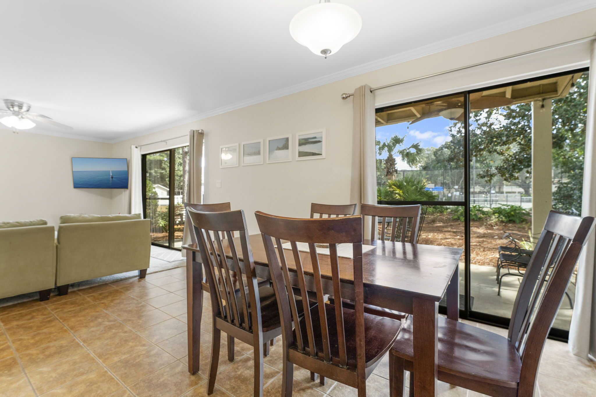 Un espace repas comprenant une grande table et des chaises, un canapé et une vue sur une terrasse extérieure, accessible par des portes vitrées.