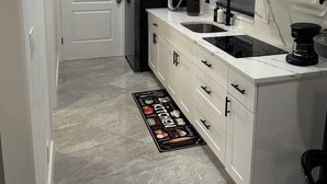 Una cocina moderna con armarios blancos, un refrigerador negro, un microondas, un fregadero y una cafetera.