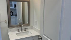 Un baño con lavamanos blanco, un espejo y una puerta.