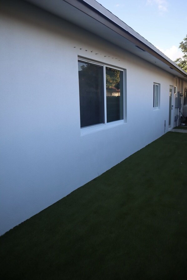 A modern building with a white exterior, a large window, and a well-maintained lawn.