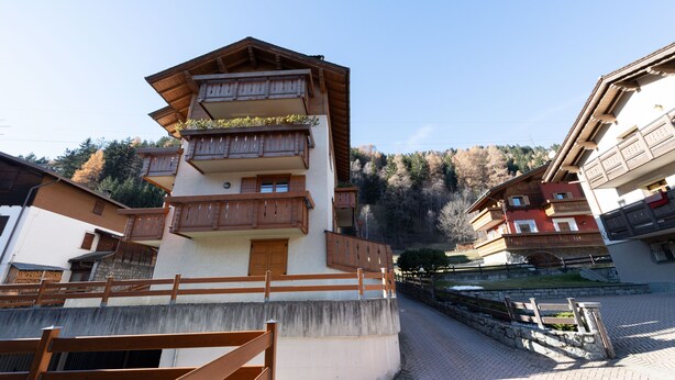 Un immeuble à plusieurs étages, doté de balcons en bois et d’une base en pierre.