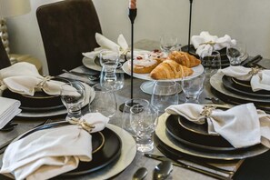Une table à manger dressée avec des assiettes noires, des serviettes blanches et des verres transparents.