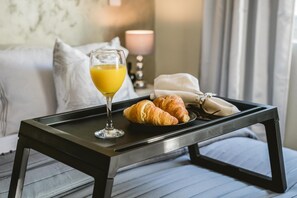 Un plateau de petit-déjeuner avec des croissants et un verre de jus d’orange, posé sur un lit.