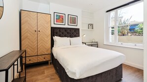Une chambre à coucher comprenant un lit, une armoire, un bureau et une fenêtre donnant sur un paysage agréable.
