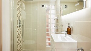Une salle de bain moderne avec une douche à l’italienne en verre, un lavabo blanc et un miroir.