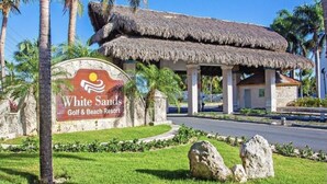 A sign for White Sands Golf & Beach Resort with a thatched-roof structure and palm trees in the background. - Beautiful 2-bed Apartment in Punta Cana (Punta Cana)