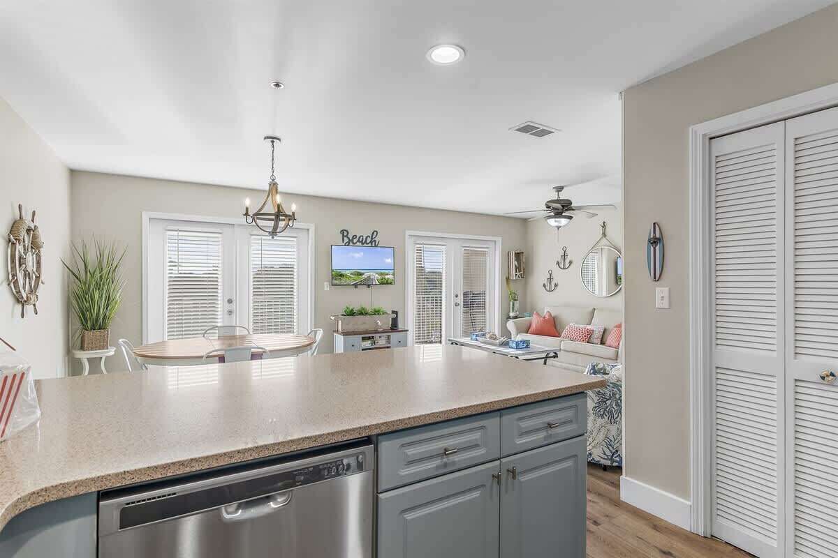 A kitchen with a central island, a dining area, and a living space with a TV.