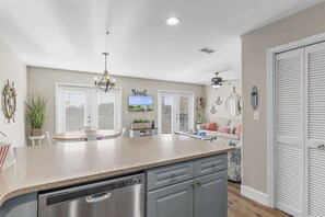 A kitchen with a central island, a dining area, and a living space with a TV.