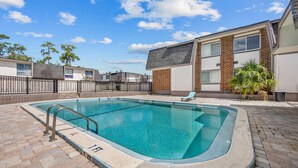 A swimming pool with a tiled deck, surrounded by a brick wall and a fence. - Walk to Shands & VA Hospital, UF, Pool Access (Gainesville)