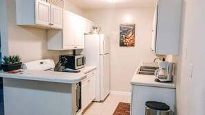 A compact kitchen with white cabinets, a microwave, a refrigerator, a coffee maker, and a trash bin. - Walk to Shands & VA Hospital, UF, Pool Access (Gainesville)