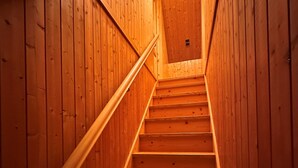 Una escalera de madera con barandilla que conduce a un techo con un respiradero.