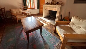Una sala de estar acogedora con chimenea, muebles de madera y una cruz en la pared.