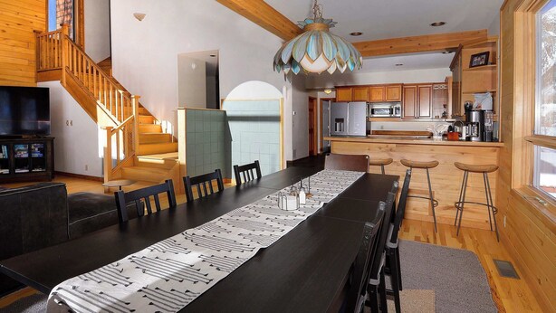 A modern kitchen with wooden cabinets, a large island, and a dining area with a long table. - Slate View, Riverbend, Garage, Fishing, Hot Tub! (Crested Butte)