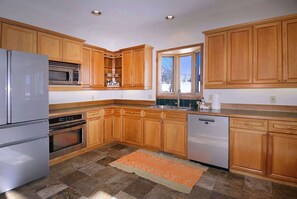 A kitchen with wooden cabinets, stainless steel appliances, and a window with a view.