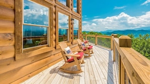 Terraza de madera con mecedoras y vistas a las montañas.