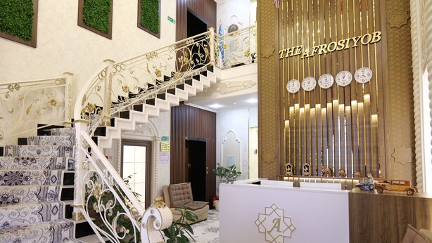 Un amplio vestíbulo con una escalera, una recepción y una pared decorada con relojes.