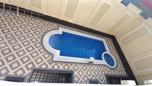 Un edificio con suelo de baldosas estampadas y zona de piscina con azulejos azules.