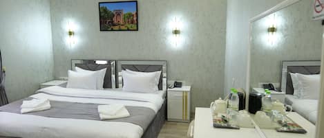 Une chambre d’hôtel moderne avec un grand lit, des tables de chevet, un miroir et un petit bureau équipé de produits de toilette.