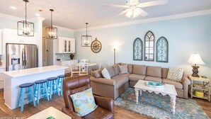 A modern living room with a sofa, a coffee table, and a dining area with stools. - 3 mins walk to Beach! Guest Beachfront Pool! (Panama City Beach)