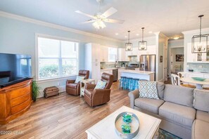 A spacious living room with a TV, leather chairs, a sofa, and a dining area with stools. - MAY DISCOUNT! 3 mins from Beach! Guest Beachfront Pool! (Panama City Beach)