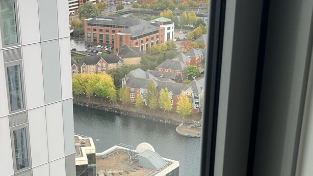Vista desde un piso alto con vista a un río, con edificios y árboles en primer plano.