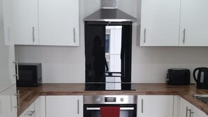 Una cocina moderna con armarios blancos, una campana extractora de acero inoxidable, un microondas y un tostador.