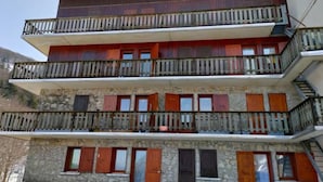 Un immeuble à plusieurs étages, doté de balcons, d’une façade en pierre et de volets en bois.