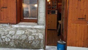 Un bâtiment rustique avec une façade en pierre, des portes en bois et une petite fenêtre.