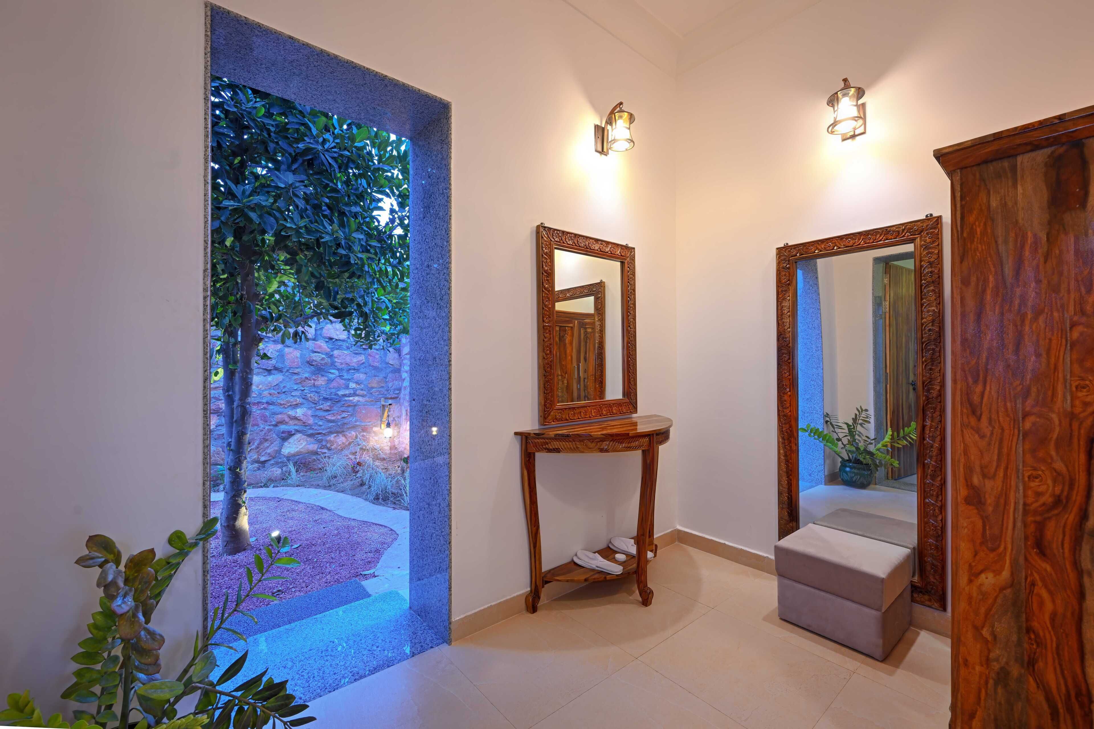 A hallway with a stone wall, a wooden console table, a mirror, and a bench.