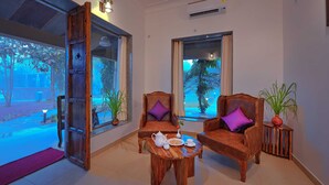 A room with two wooden chairs, a small wooden table, and a window with curtains.