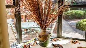Une fenêtre sur le rebord de laquelle sont posés un vase contenant des roseaux séchés et de petites figurines.