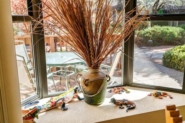 Une fenêtre sur le rebord de laquelle sont posés un vase contenant des roseaux séchés et de petites figurines.