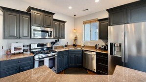 A modern kitchen with grey cabinets, stainless steel appliances, and a granite countertop. - Desert Hideaway: 3-Bedroom Home with Year-Round Private Pool & Hot Tub (Moab)