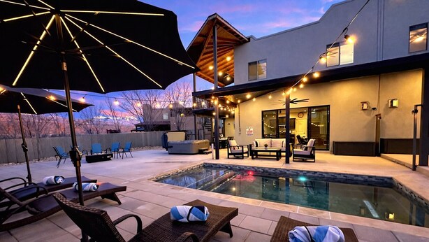 A pool area with lounge chairs, umbrellas, and string lights. - Exclusive Retreats Desert Hideaway 3 Bedroom all Suite home with Private pool #2 (Moab)