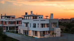 Un edificio residencial moderno de varios pisos con techo plano, ventanas amplias y una piscina.