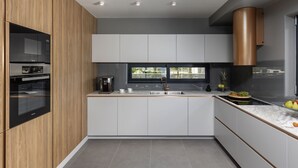 Una cocina moderna con electrodomésticos integrados, un ventanal grande y una campana extractora de cobre.