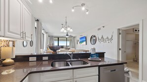 Une cuisine moderne dotée d’un îlot central, d’un lave-vaisselle et offrant une vue sur l’espace de vie.