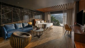 Una habitación de hotel moderna con una cama grande, un sofá, una mesa de centro y un televisor.